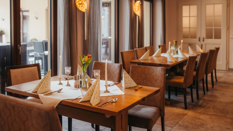 Pub with cabaret evenings and morning pint, © Niederösterreich Werbung/Daniela Führer A cozy table in an inn with candles and flowers.
