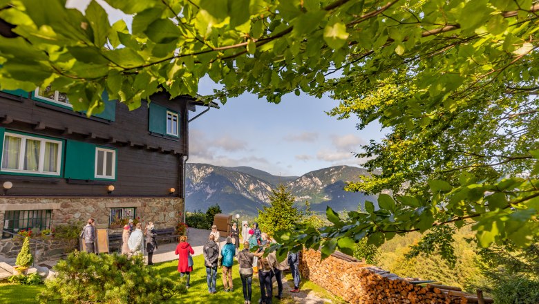 Looshaus am Kreuzberg, © Wiener Alpen / Christian Kremsl Group of people in front of the Looshaus on the Kreuzberg with a mountain landscape in the background.