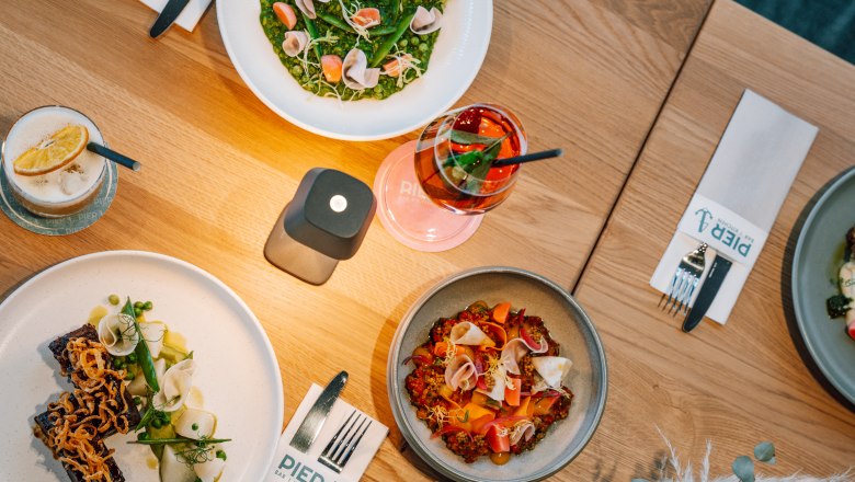 Various dishes and drinks on a wooden table in the Pier 4 restaurant.