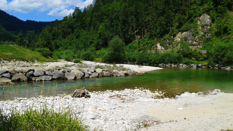 River landscape with clear water, pebble beach and wooded hills.