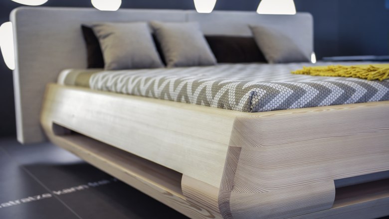 Modern bed with wooden frame and patterned comforter cover.