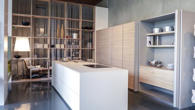 Modern kitchen with white island, shelves and wood paneling.