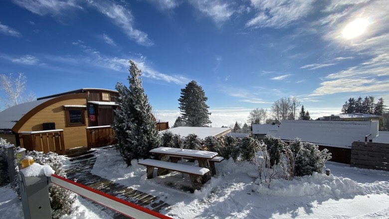 Glamping Park in winter, © Glamping-Park Mönichkirchen OG Winter glamping hut covered in snow, surrounded by trees and blue sky.