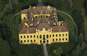 Aerial view of Eckartsau Castle, surrounded by trees and gardens.