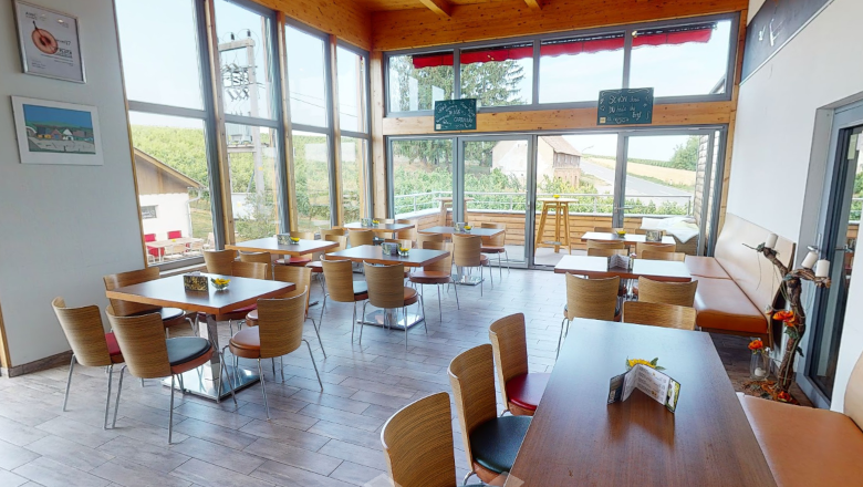 Interior view of a modern wine tavern with wooden furniture and large windows.