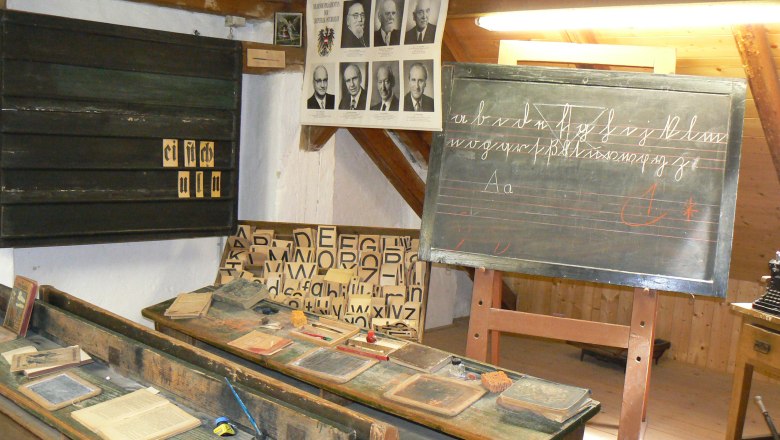 Historic classroom with blackboard, desk and teaching materials.