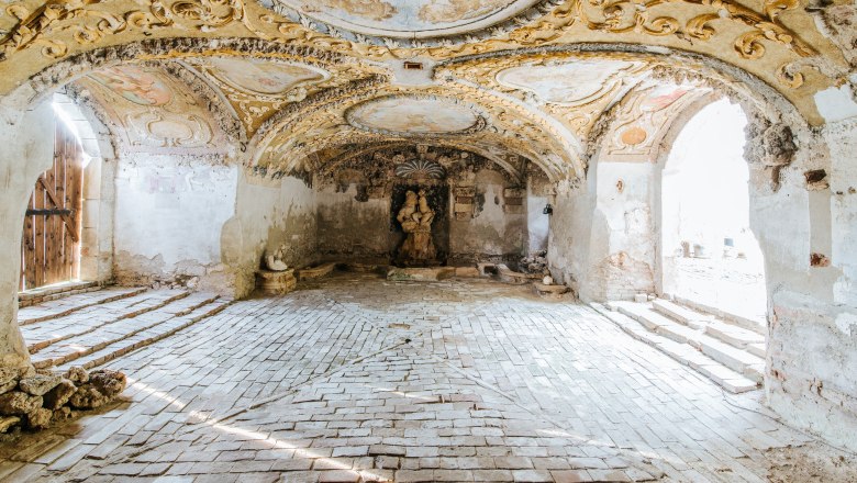 Historic room with ornate ceilings and a statue in the center.