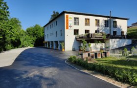 Building with the inscription 'Brandtner', surrounded by trees and a parking lot.