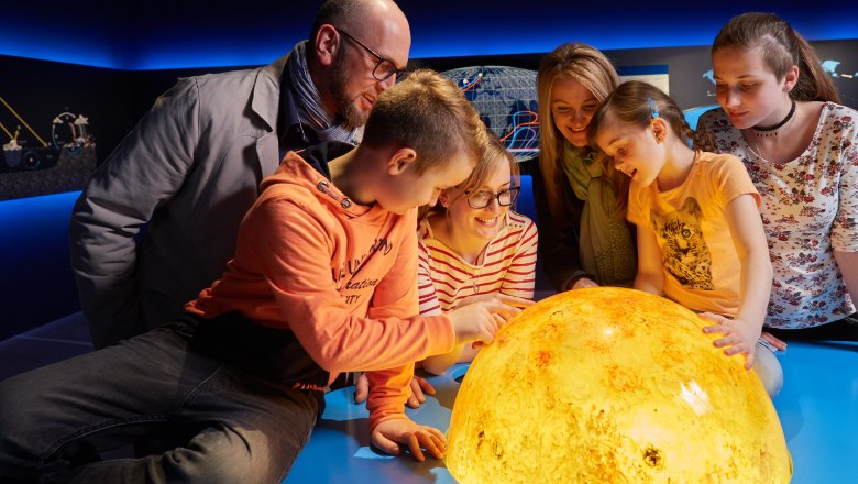 Group of people looking at a luminous model of the sun.