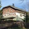 A traditional building with wooden cladding and balcony, surrounded by trees and a wooden fence. Sign: "Döhler shelter".