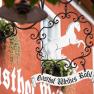 Metal sign with a white horse and the words 'Gasthof Weißes Rößl' in front of a red building.