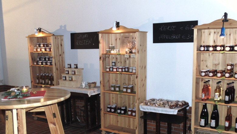 Interior view of a farm store with shelves full of jams, juices and cookies.