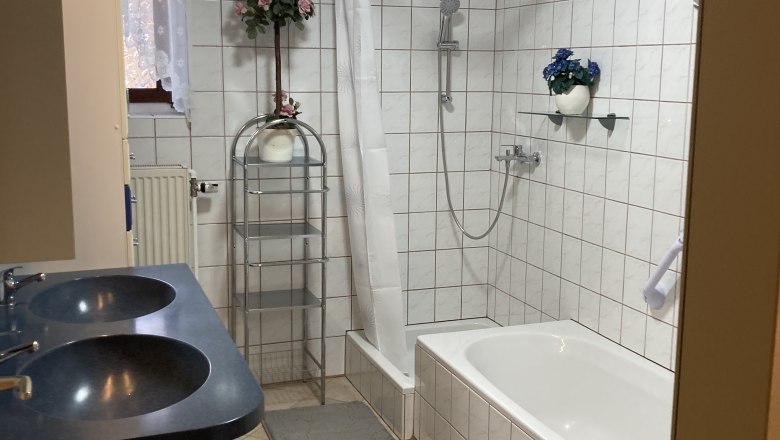 Bathroom with bathtub, double washbasin and shower with shower curtain.