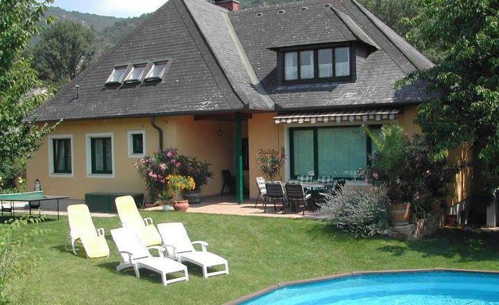 A house with a garden, pool and sun loungers.