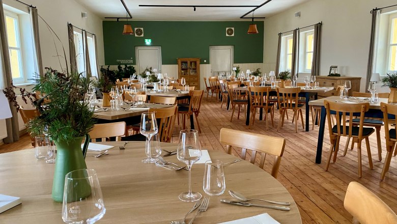 Modern hall on the upper floor of the inn, with original wooden floor, wooden tables and armchairs.
