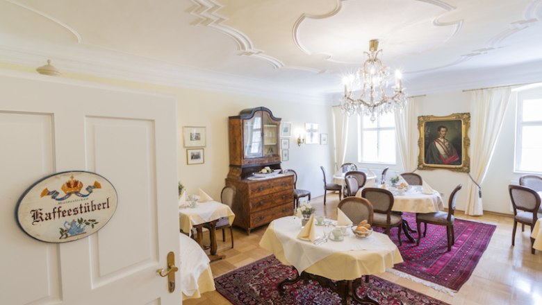 Elegant baroque-style café with chandelier and antique furniture.