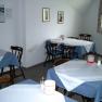 A breakfast room with several tables set with blue and white tablecloths.