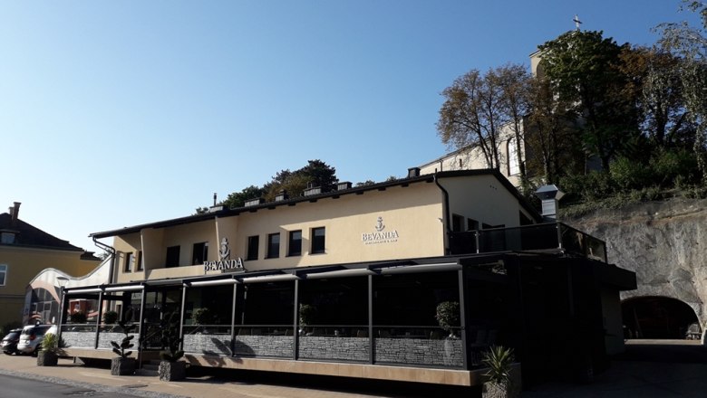 Building with the inscription 'Bevanda' and terrace, surrounded by trees and rocks.