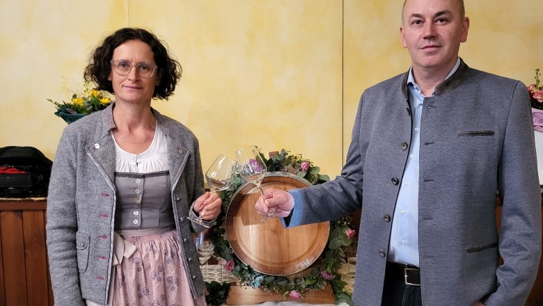 Two people standing in front of a wooden barrel