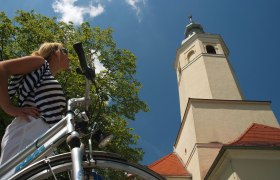 Woman with bicycle in front of the pilgrimage church Maria Moos.