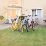 Three bicycles are parked on a lawn in front of the Thermenblick guest house.