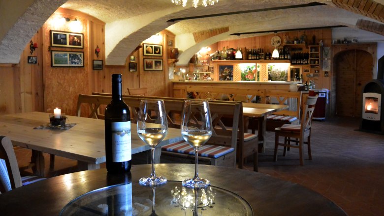 Cozy wine cellar with wooden furniture, wine bottles and glasses on a table.