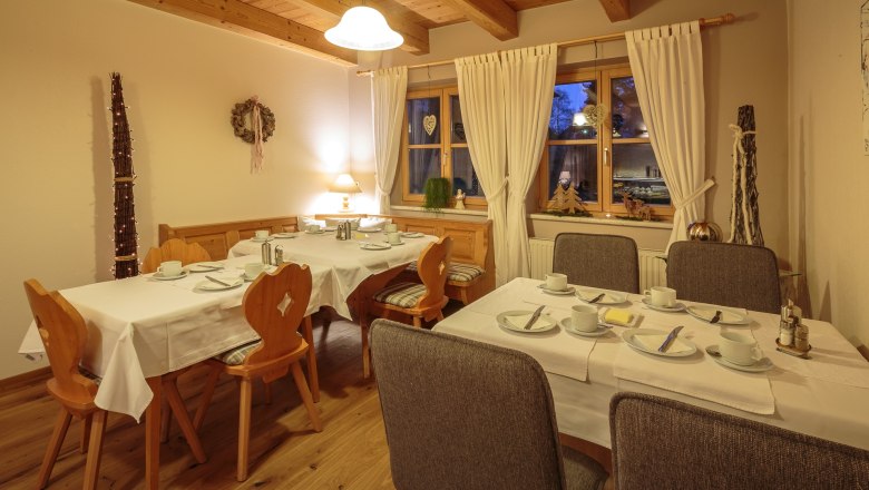 Cozy breakfast room with laid tables, wooden furniture and decorations.