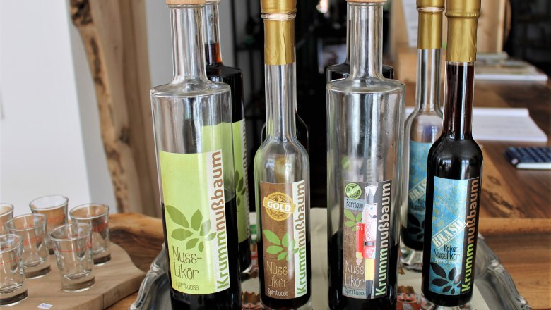 Several bottles of nut liqueur on a tray with glasses next to them.