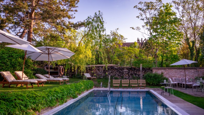 Hotel Landhaus Moserhof, © Niederösterreich Werbung / Maximilian Pawlikowsky Garden with pool, sun loungers and parasols at Hotel Landhaus Moserhof.