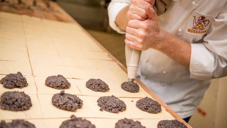 A baker sprays dough onto a baking tray in a bakery.