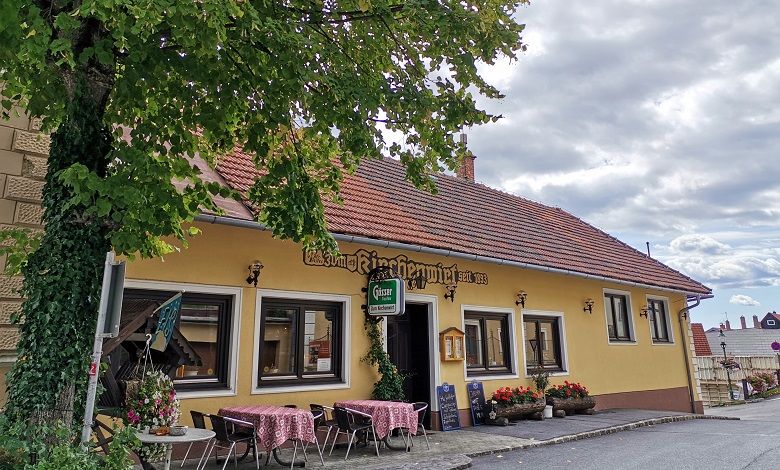 Exterior view of a traditional inn with a yellow façade and red roof tiles.