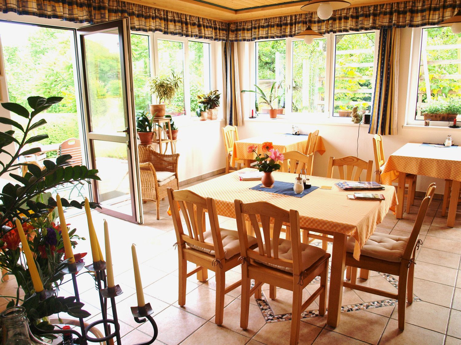 A bright conservatory with wooden furniture, plants and large windows that let in plenty of light.