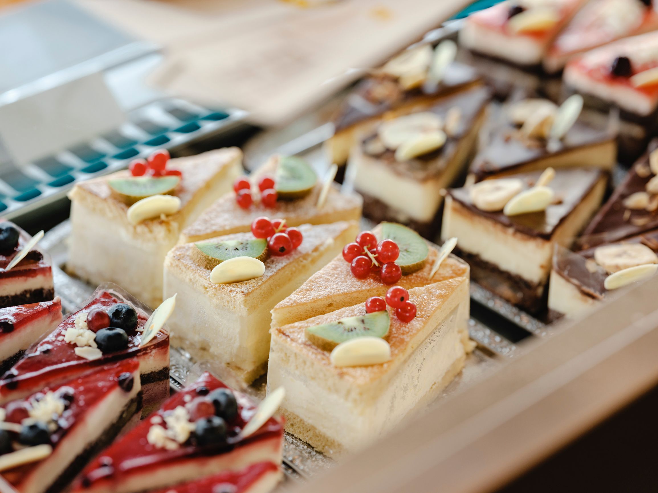 Various pieces of cake in a display case, decorated with fruit and chocolate.