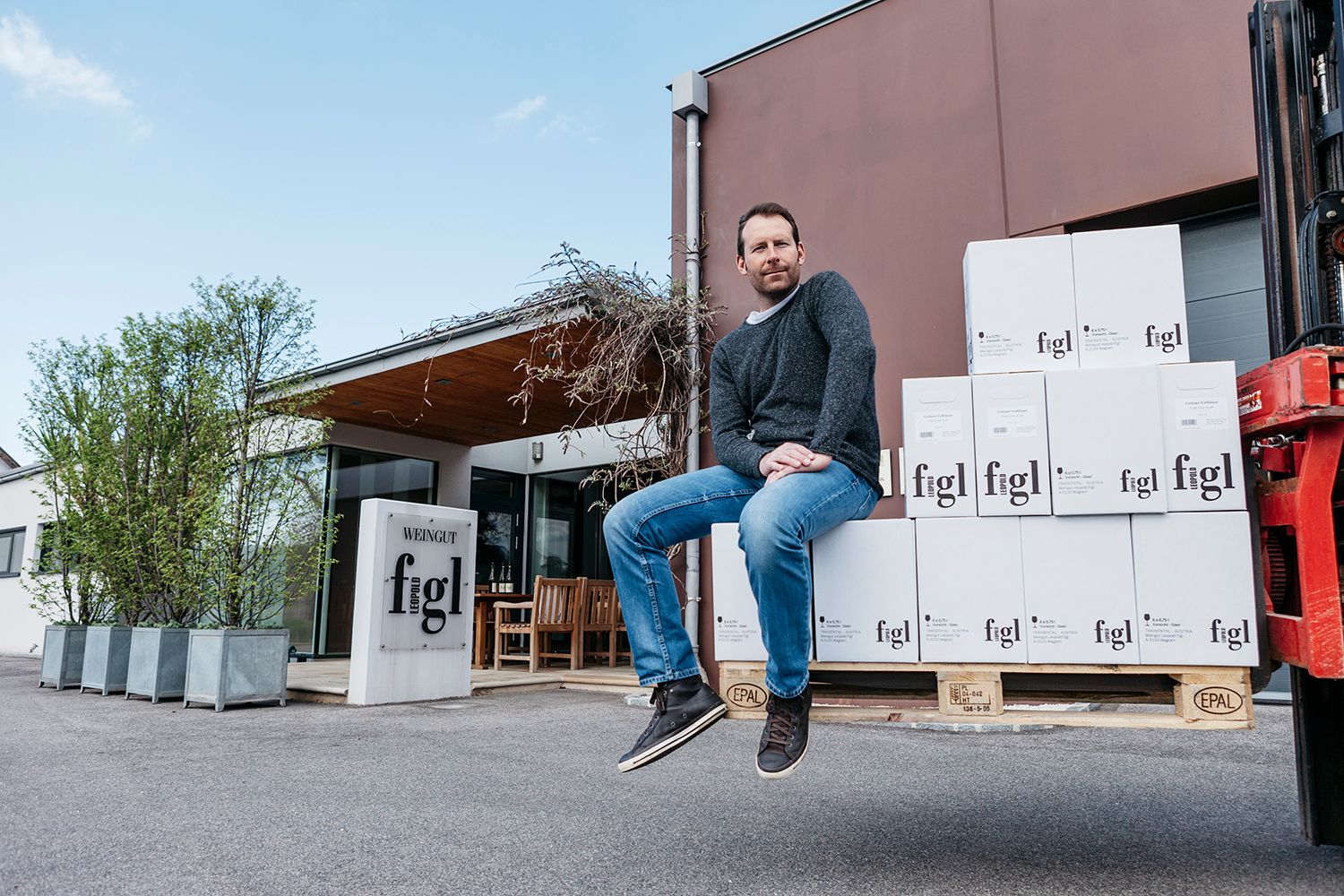 A man sits on stacked wine cartons in front of the Leopold Figl winery.