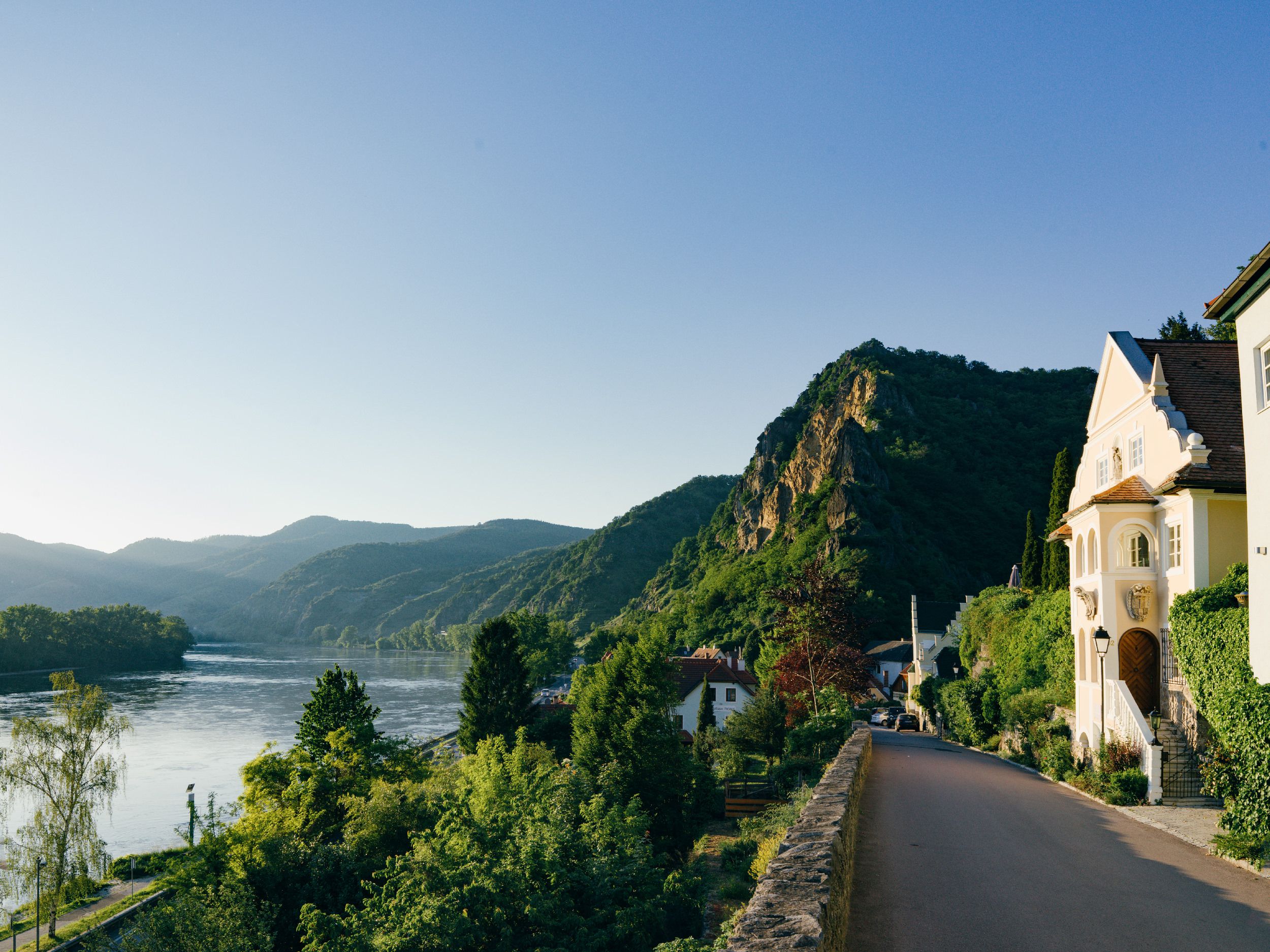 Landscape with river, mountains and houses at sunset.