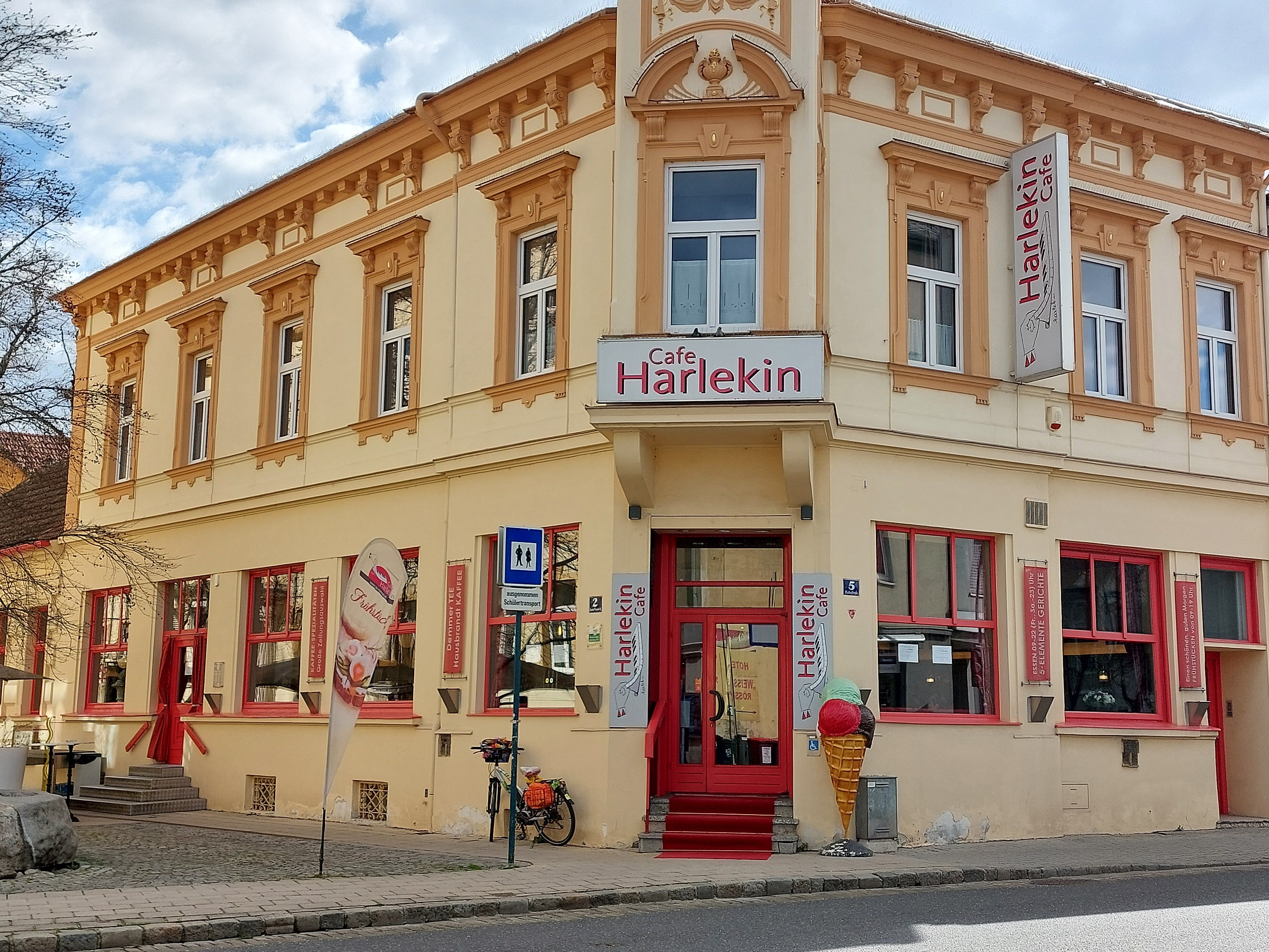 Exterior view of Cafe Restaurant Harlekin with yellow façade and red windows.