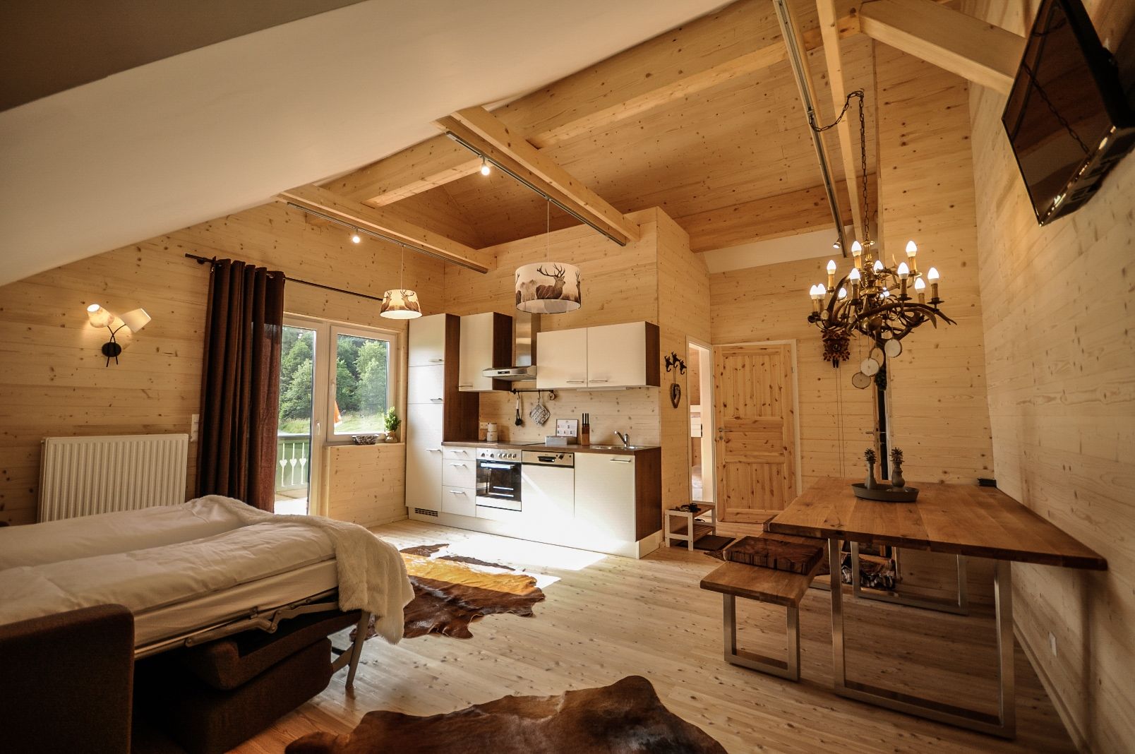 Cozy apartment with wooden walls, kitchen, dining table and bed.