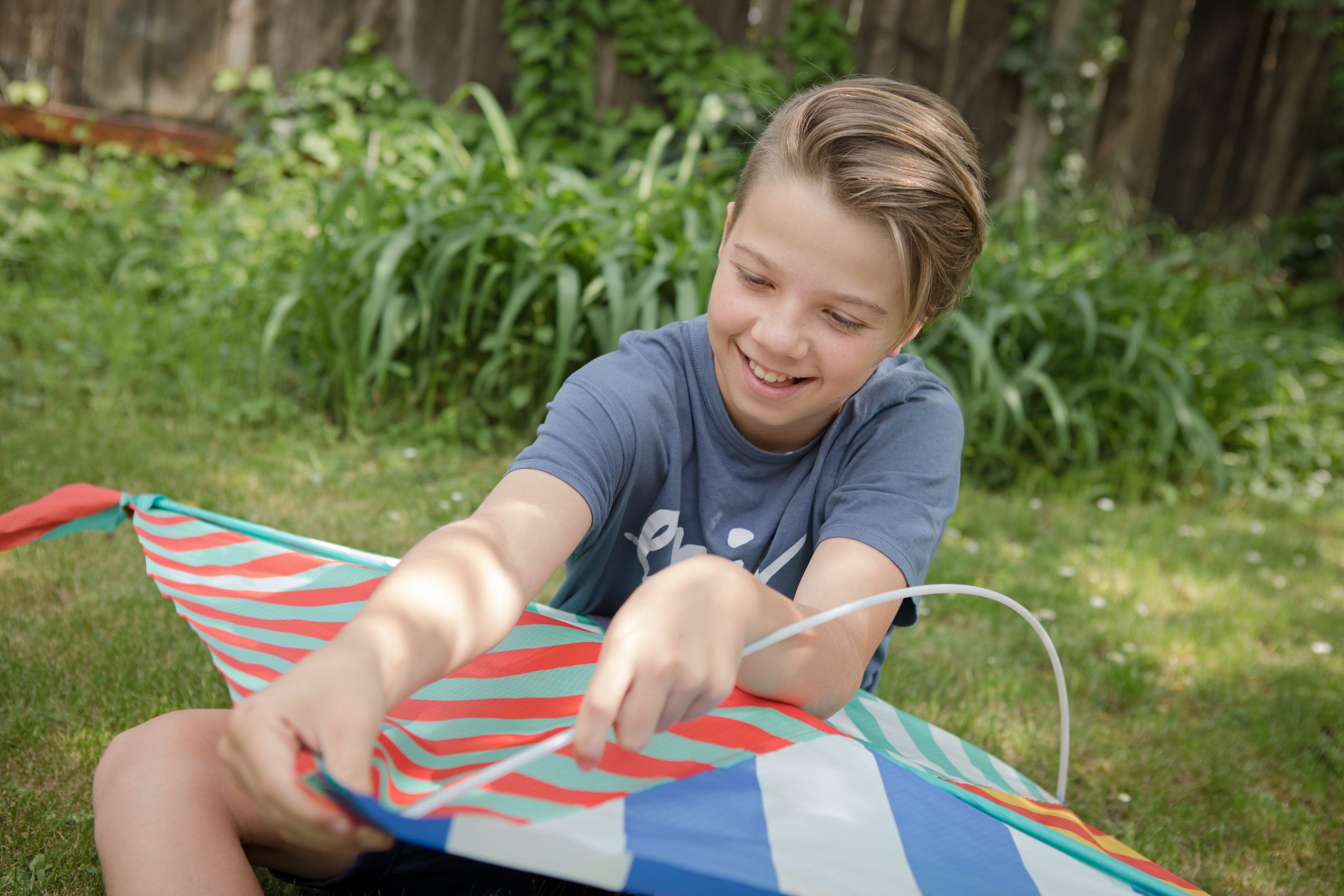 A child sits in the grass holding a colorful kite.