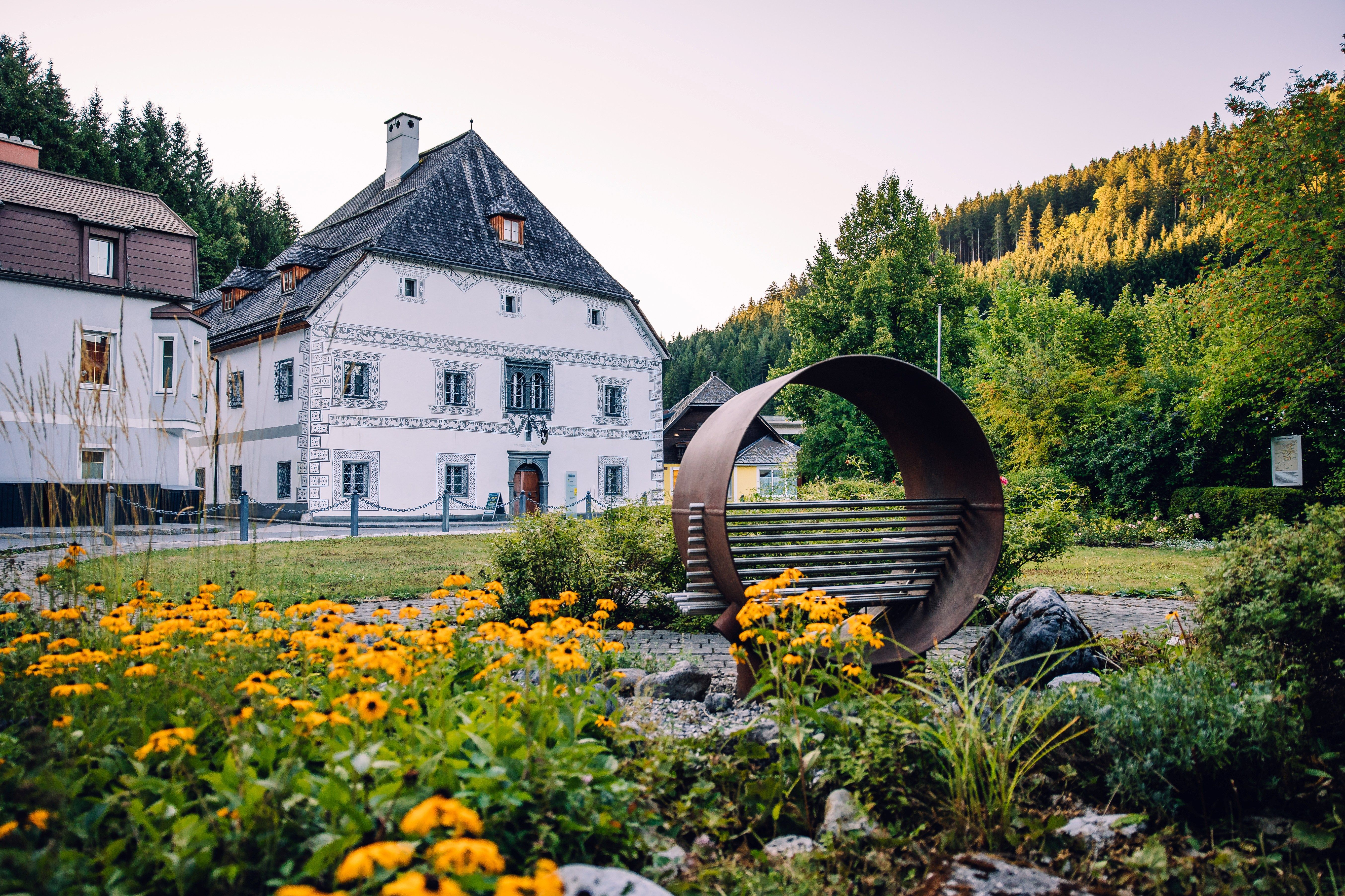Amonhaus in Lunz am See, with a recliner in the foreground and a flower bed in front of the historic building.