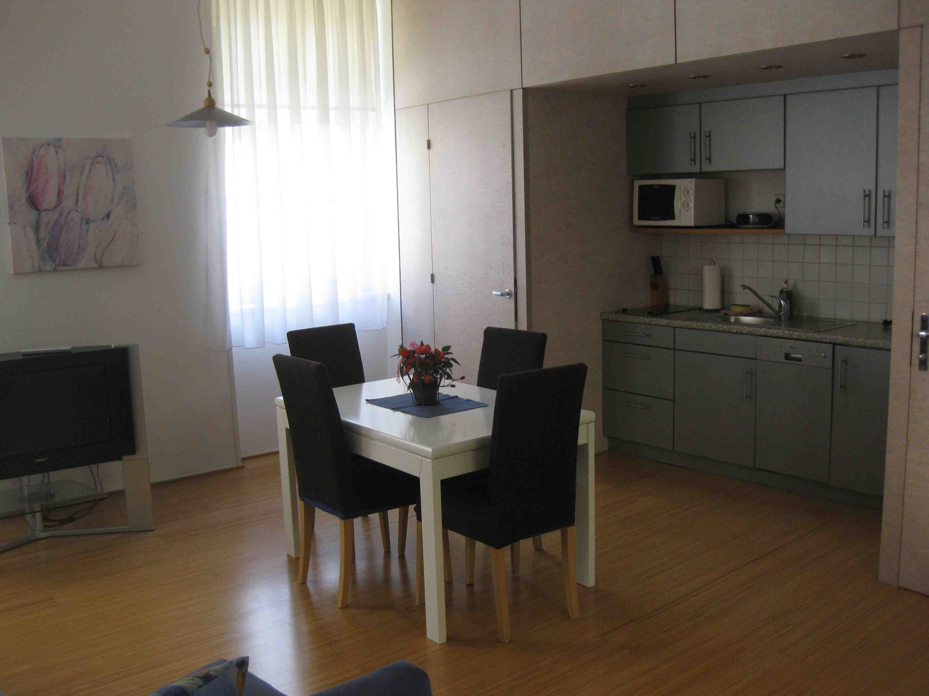 Gray kitchenette with dining table and blue chairs.