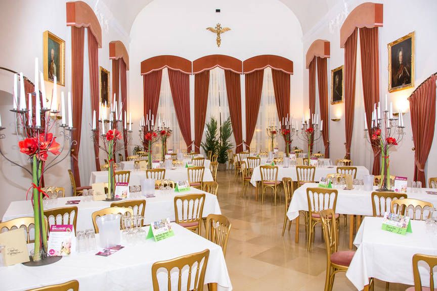 Elegant hall with laid tables, candlesticks and red curtains.