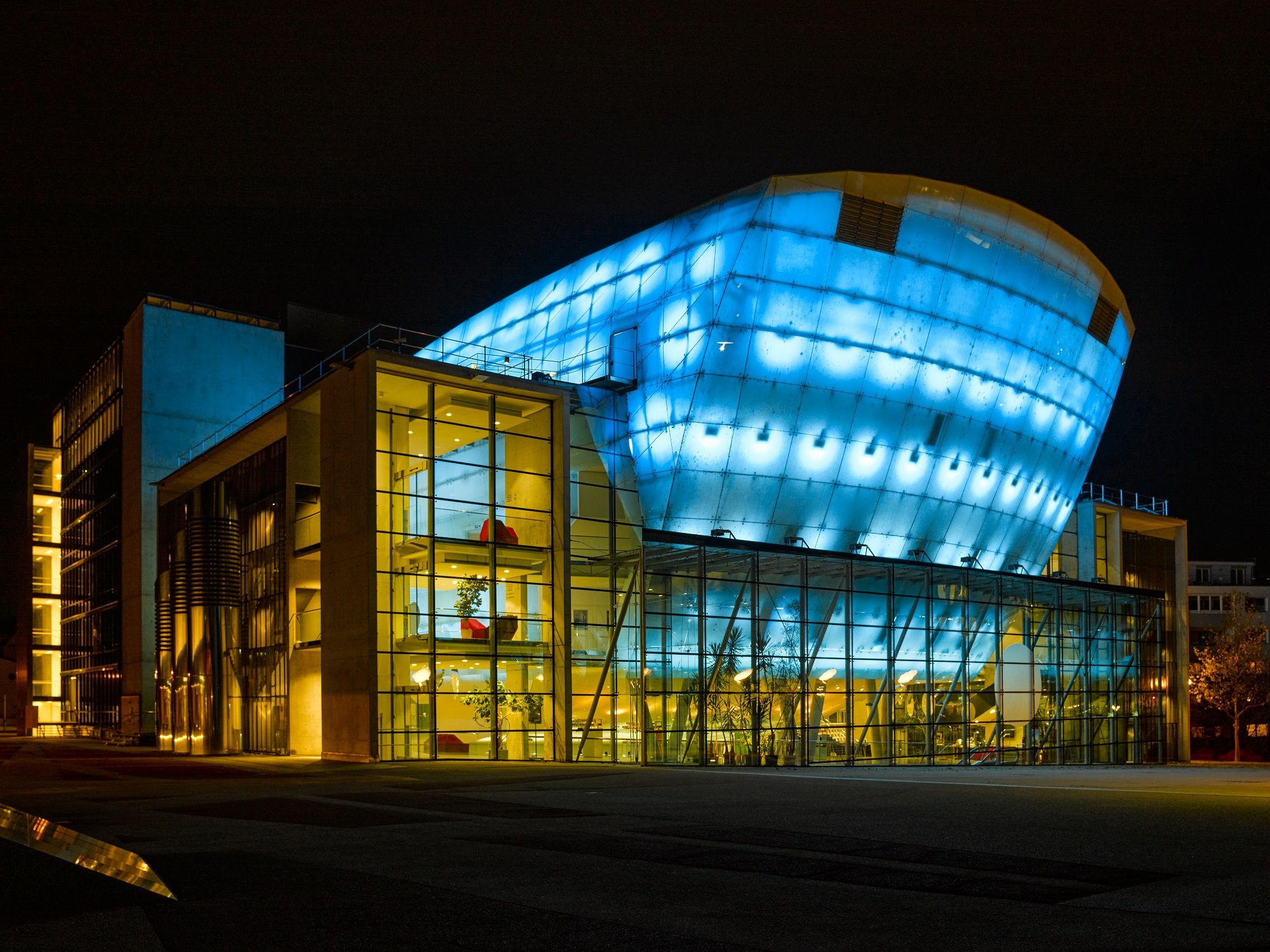 Festspielhaus St. Pölten at night, illuminated in blue and yellow.