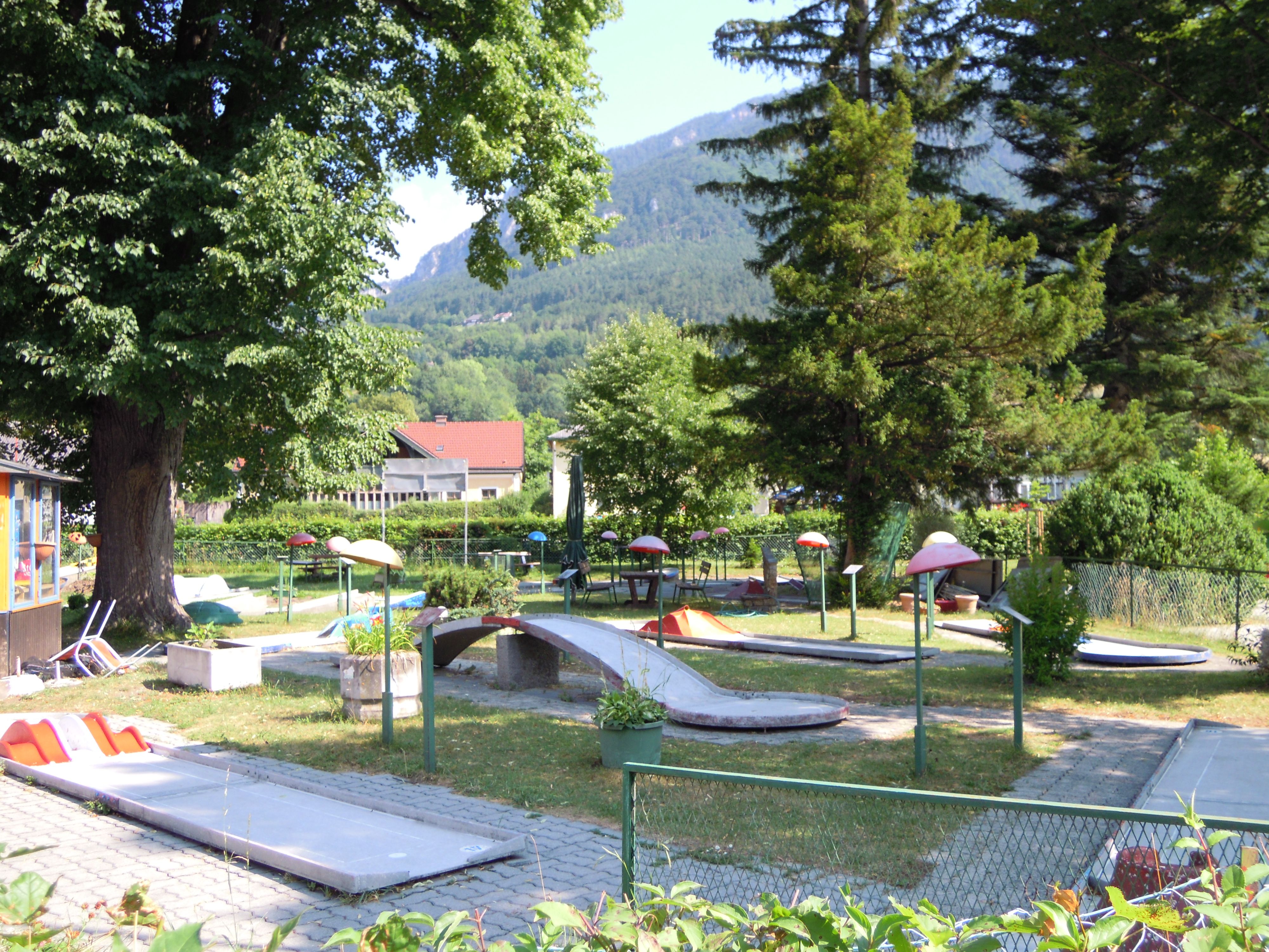 Minigolf course in Payerbach with trees and mountains in the background.