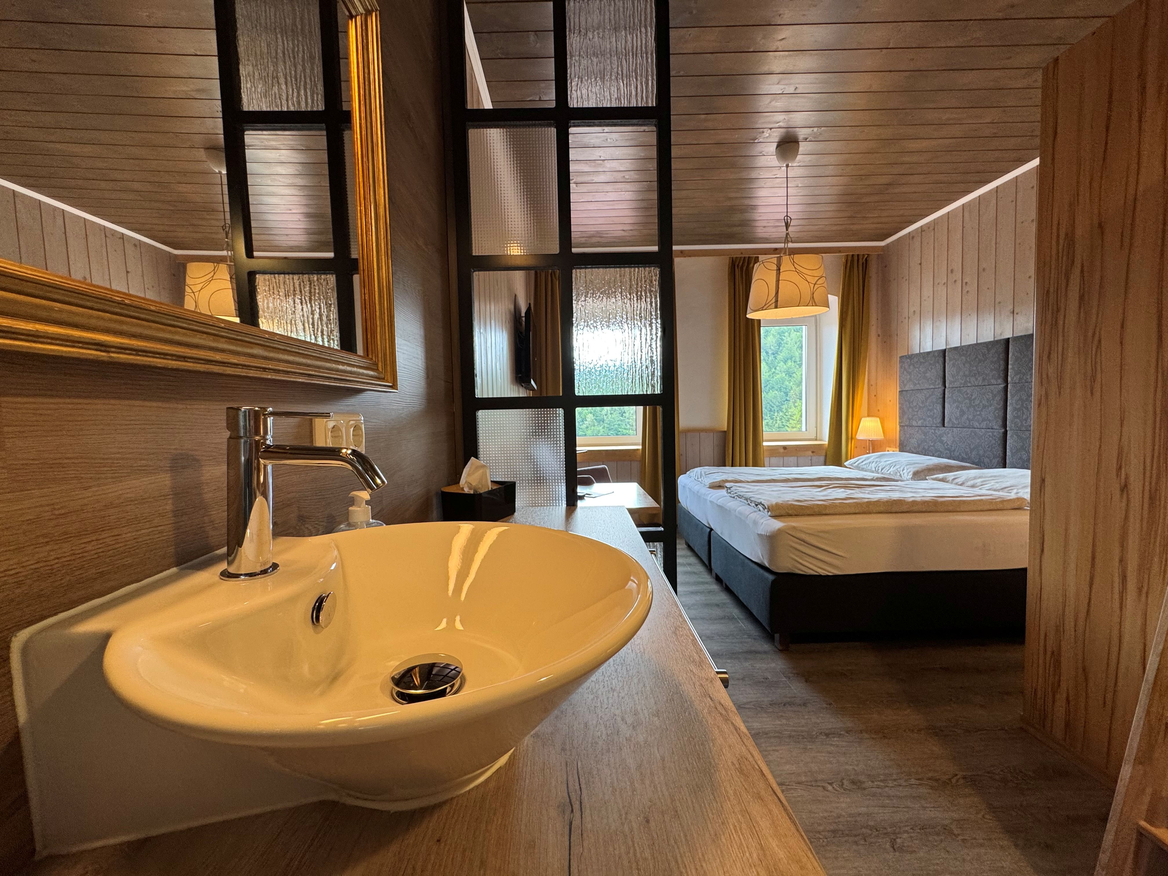 Interior view of a cozy room with a sink, a double bed, and wood paneling.