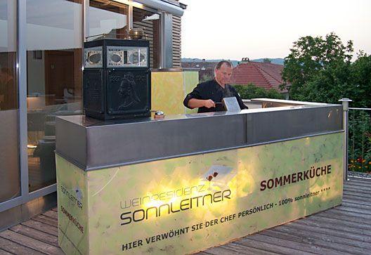 A chef prepares meals in an outdoor kitchen at the Sonnleitner wine residence.