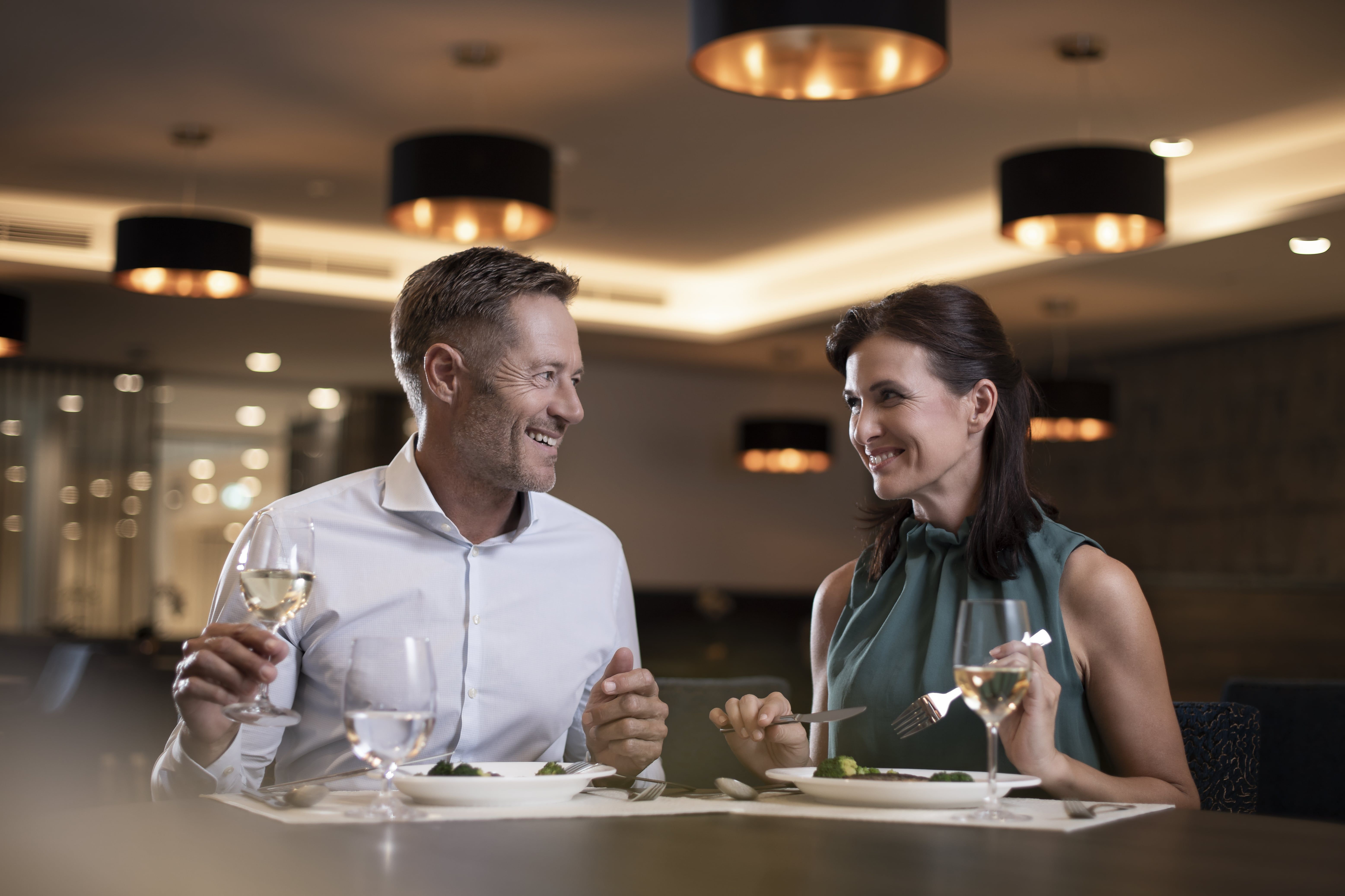 A couple is sitting in an elegant restaurant enjoying a dinner with wine.