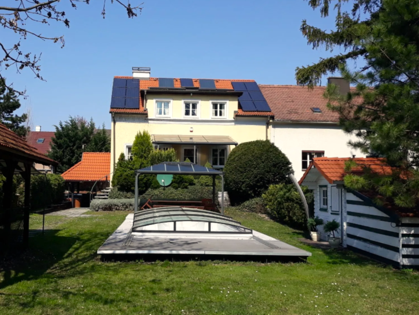 A house with solar panels and a covered pool in the garden.