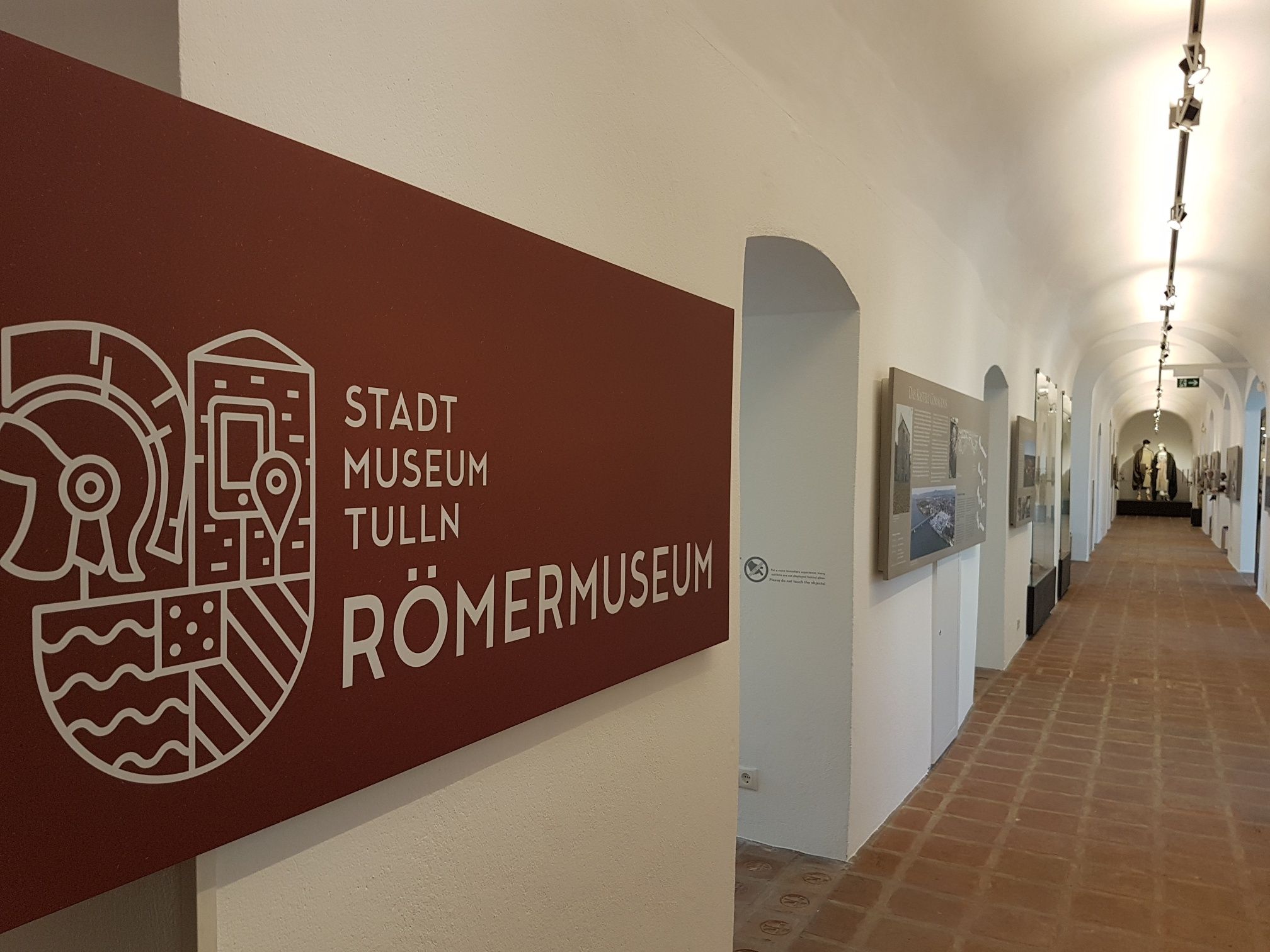 Interior view of the Tulln City Museum Roman Museum with a long corridor and exhibits on the walls.