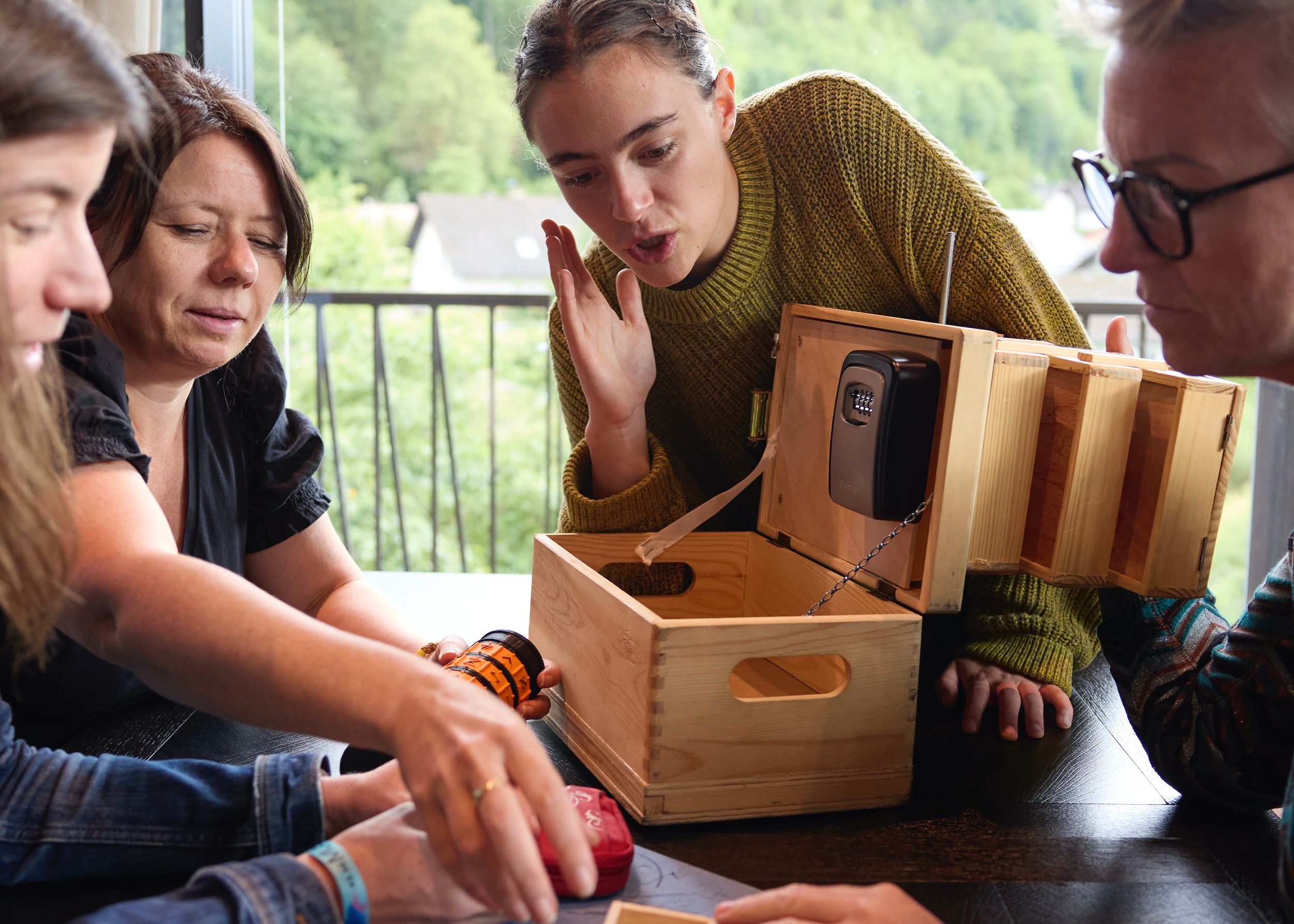 Four people work together on a wooden box with a combination lock.