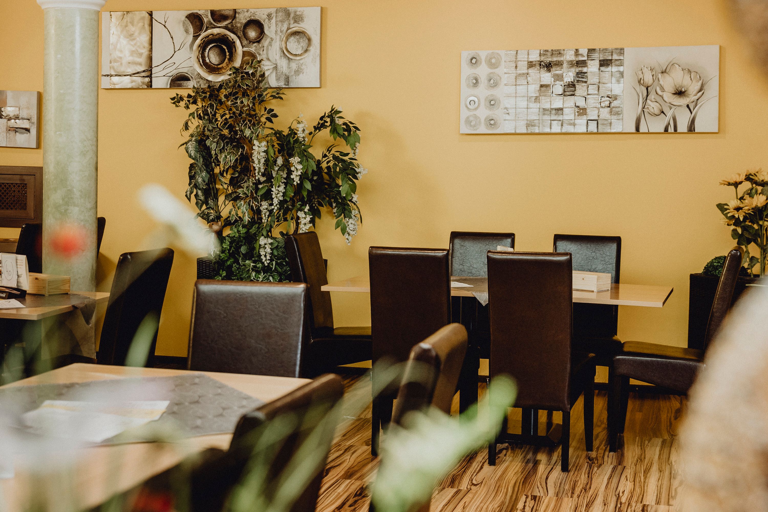 Cozy restaurant with yellow walls, plants and modern art.